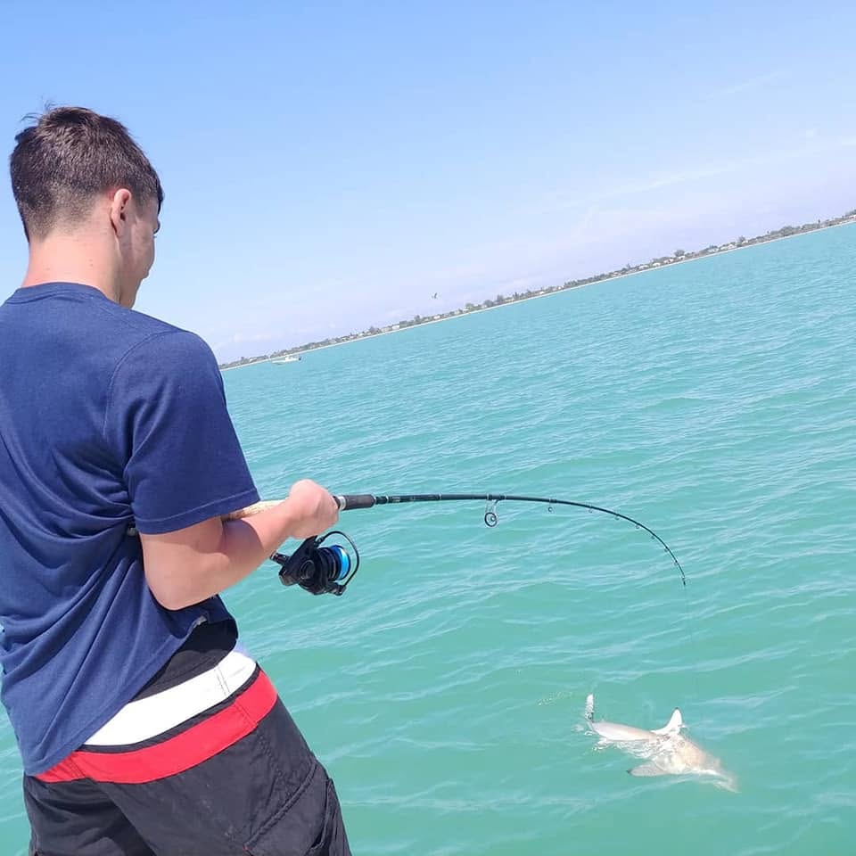 Angler fighting a shark hooked near the beach surf zone