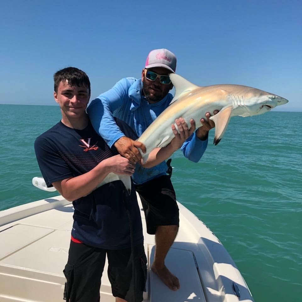 angler and captain Erik holding a blacktip shark with dark-tipped fins in Fort Myers